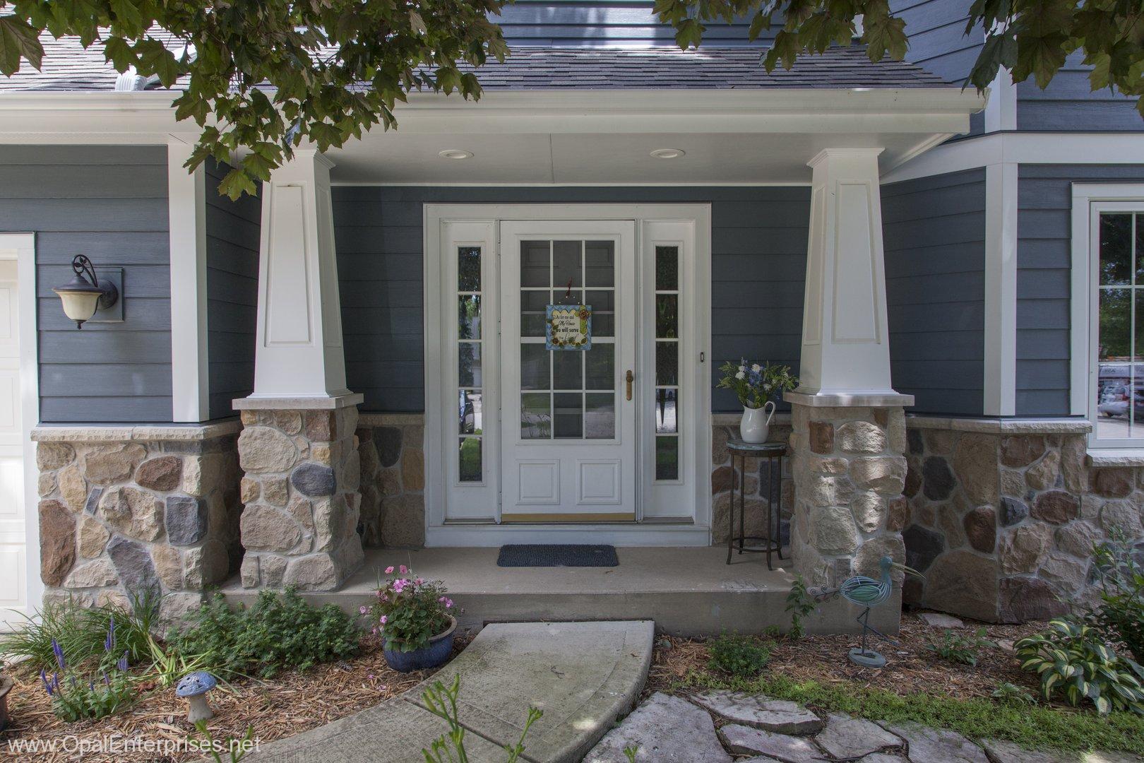 Inviting elegant entry on blue house with stone accents and decorative columns #OpalCurbAppeal