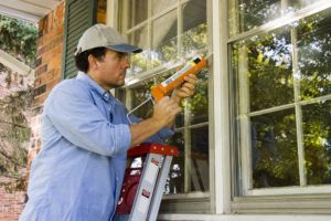 man caulking window exterior