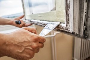 repairman scraping wood frame window