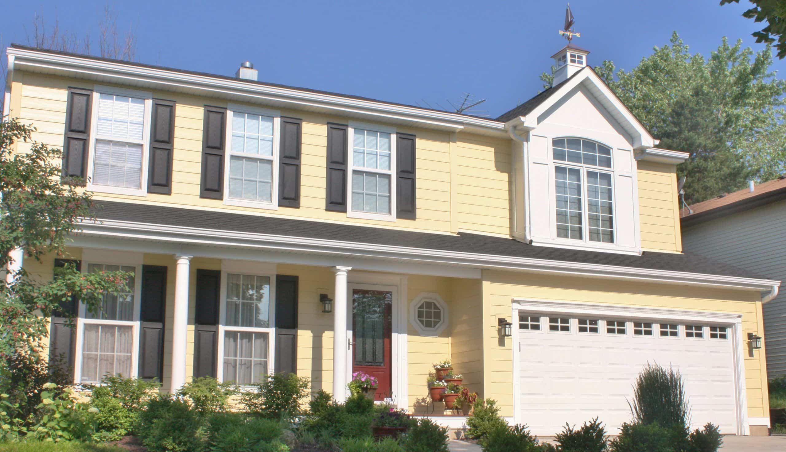 two-story home with yellow siding and red door