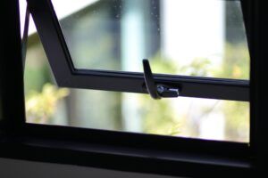 A black awning window is open and shows green grass outside.