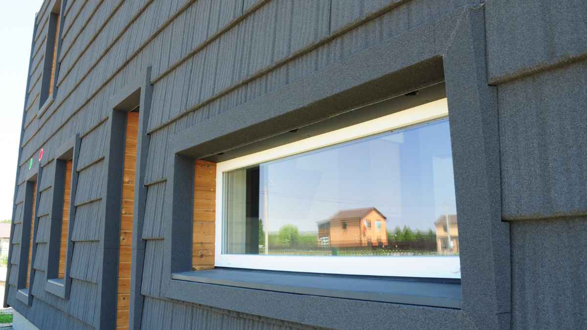 A close-up view of a modern building facade featuring a energy-efficient window with a reflective surface.